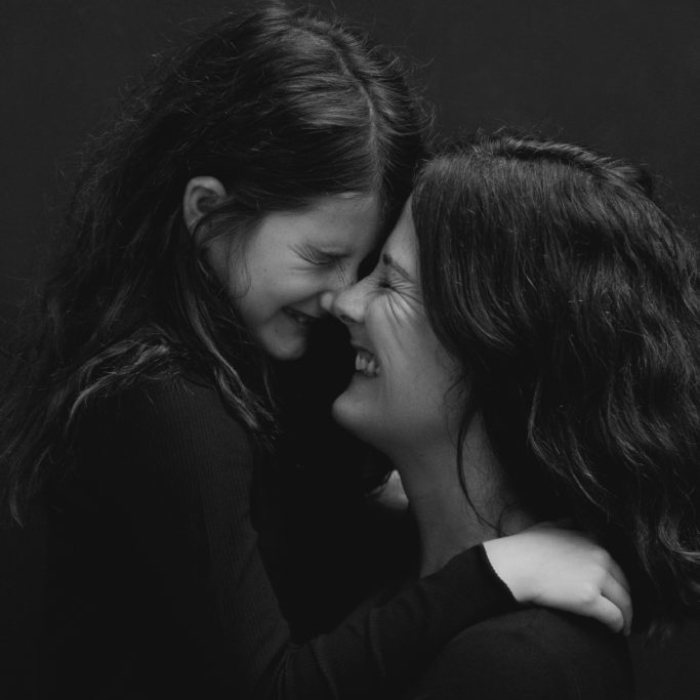 Black and white images of a young girl and mother laughing with noses touching