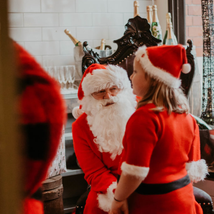 child dressed as father christmas whilst meeting santa