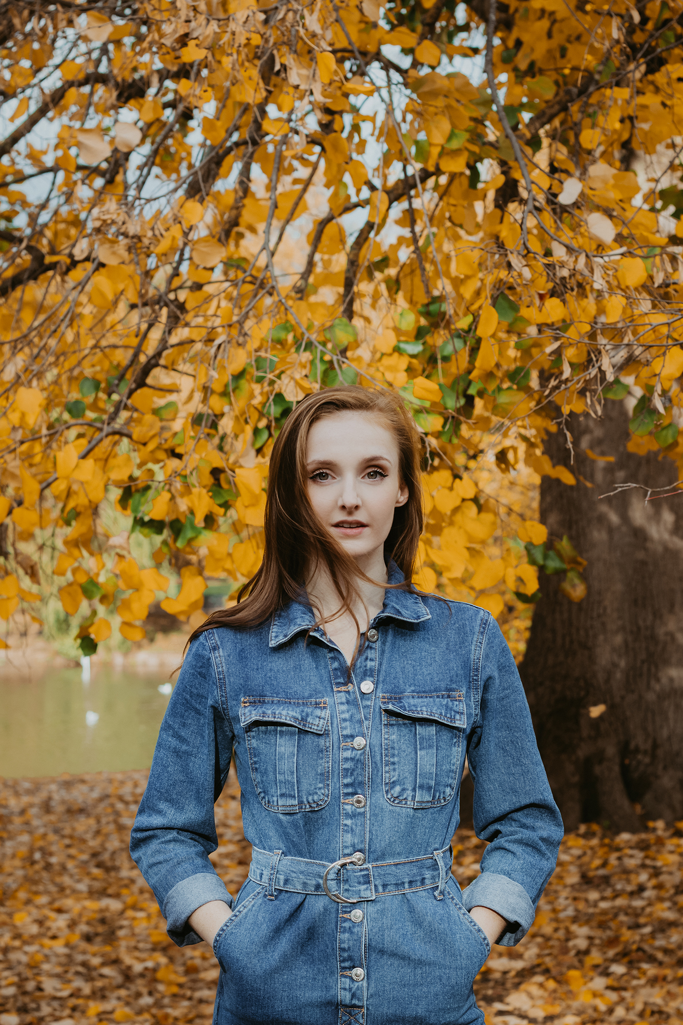 white girl with ginger long hair wearing denim in park with orange autumn leaves