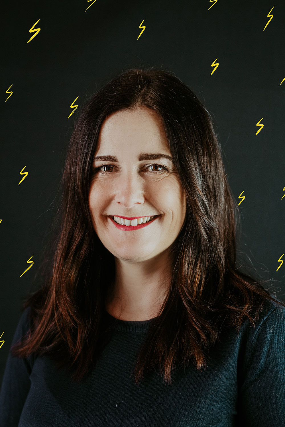 brunette woman against black background with yellow lightning bolts in background
